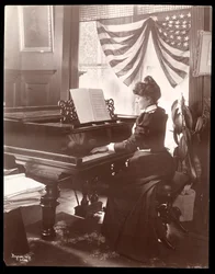 Mrs. Florence Clinton Sutro playing the piano in her home at 320 West 102nd Street, New York